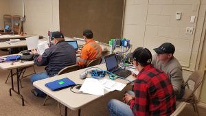 Students working in pairs in a classroom on some networking equipement